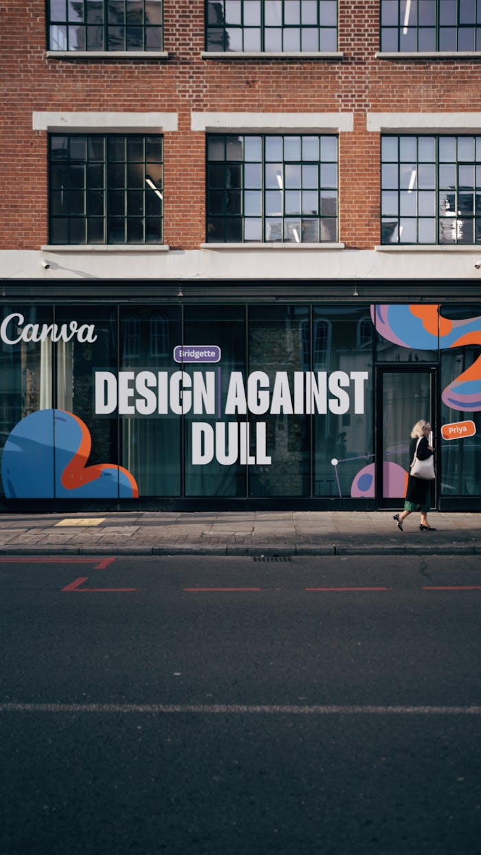 Street mural with 'Design Against Dull' slogan on a modern urban building facade.